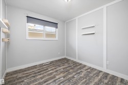 Bright room featuring wood-finish flooring, white baseboards, and a window with a roller shade - 