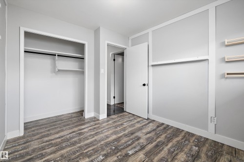 Spacious room featuring wood-finish flooring, light grey walls with white trim, and a built-in closet with shelving and hanging rod - 11525 37A Avenue Nw, Edmonton, AB - Indoor Photo Showing Other Room