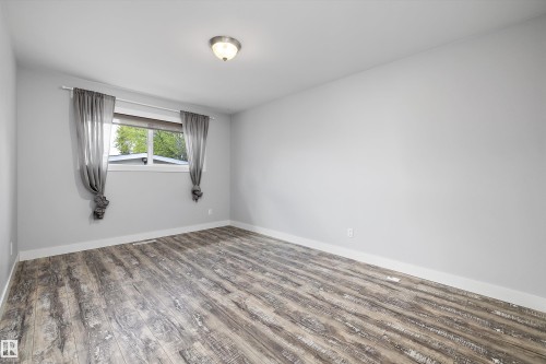 Spacious room featuring wood-finish flooring and light gray walls - 11525 37A Avenue Nw, Edmonton, AB - Indoor Photo Showing Other Room