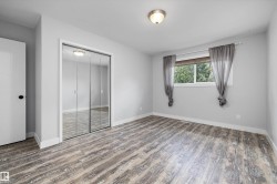 Spacious room featuring wood-finish flooring, a large window, mirrored closet doors, and recessed lighting - 