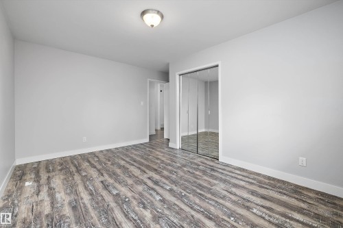 Spacious room featuring wood-finish flooring, light gray wall color, white trim, and a ceiling-mounted light fixture - 11525 37A Avenue Nw, Edmonton, AB - Indoor Photo Showing Other Room
