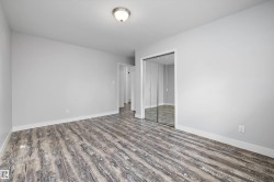 Spacious room featuring wood-finish flooring, light gray wall color, white trim, and a ceiling-mounted light fixture - 