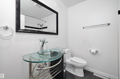 Bathroom featuring a glass vessel sink, chrome fixtures, a modern toilet, black-framed mirror, and dark tile flooring - 11525 37A Avenue Nw, Edmonton, AB - Indoor Photo Showing Bathroom