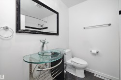 Bathroom featuring a glass vessel sink, chrome fixtures, a modern toilet, black-framed mirror, and dark tile flooring - 