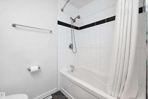 White tiled shower and tub combination featuring a dark accent tile band - 11525 37A Avenue Nw, Edmonton, AB - Indoor Photo Showing Bathroom