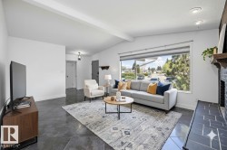 Spacious living area featuring a large picture window, vaulted ceiling with exposed beam, recessed lighting, and dark tile flooring - 