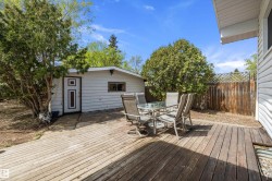 Rear wooden deck with an outdoor structure featuring white siding and a paneled door - 