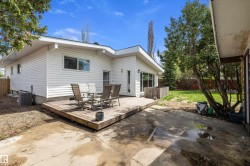 Expansive wood deck with a white siding exterior and mature trees - 