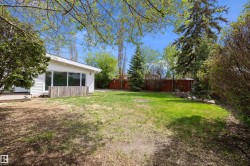 Expansive backyard featuring a manicured lawn, mature trees, and a privacy fence - 