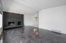 Spacious interior featuring large format dark grey tile flooring, a prominent black brick fireplace with a raised hearth, and recessed lighting - 11525 37A Avenue Nw, Edmonton, AB  - Indoor Photo Showing Other Room With Fireplace 
