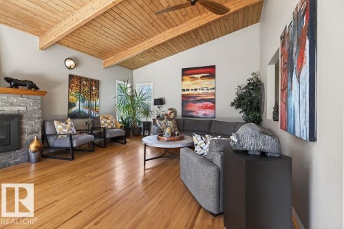 Sun-filled living room features vaulted ceiling, gas fireplace with marble surround and patio access - 49 52257 Rge Road 231, Rural Strathcona County, AB 