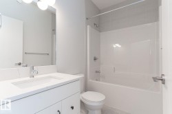 Bathroom vanity featuring a polished chrome faucet, integrated rectangular sink, and stone-finish countertop - 