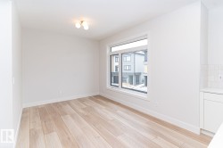 Bright room featuring light wood-finish flooring, white walls, and a large window - 