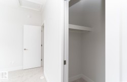 Clean white interior featuring light-toned carpet, a contemporary interior door with brushed nickel hardware, and a closet with integrated shelving and hanging rod - 