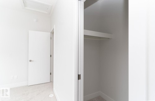 Clean white interior featuring light-toned carpet, a contemporary interior door with brushed nickel hardware, and a closet with integrated shelving and hanging rod - 53 7121 May Crescent, Edmonton, AB - Indoor Photo Showing Other Room