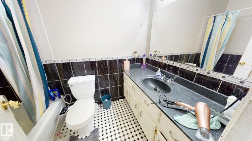 Bathroom featuring a built-in vanity with an integrated sink, black speckled countertop, and wall-mounted mirror - 402 2624 Millwoods East Road E, Edmonton, AB - Indoor Photo Showing Bathroom