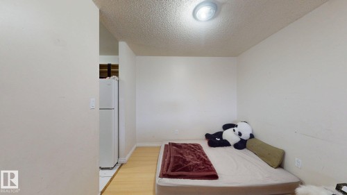 Compact sleeping area featuring light-toned wood-finish flooring and a ceiling-mounted light fixture - 402 2624 Millwoods East Road E, Edmonton, AB - Indoor Photo Showing Bedroom