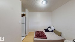Compact sleeping area featuring light-toned wood-finish flooring and a ceiling-mounted light fixture - 