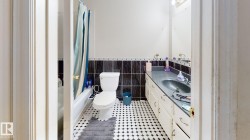 Bathroom featuring black and white mosaic floor tile, a white toilet, and a vanity with an integrated sink and cabinet storage - 