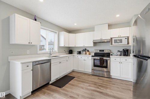Kitchen featuring white cabinetry, light-toned countertops, and wood-finish flooring - 11 3380 28A Avenue Nw, Edmonton, AB - Indoor