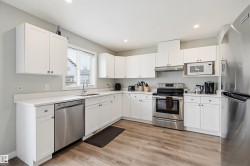 Kitchen featuring white cabinetry, light-toned countertops, and wood-finish flooring - 