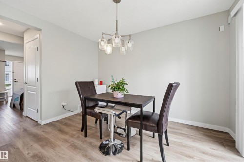 Dining area featuring wood-finish flooring, light grey painted walls, and a contemporary multi-bulb chandelier - 11 3380 28A Avenue Nw, Edmonton, AB - Indoor Photo Showing Dining Room