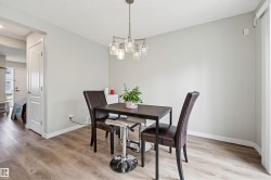 Dining area featuring wood-finish flooring, light grey painted walls, and a contemporary multi-bulb chandelier - 