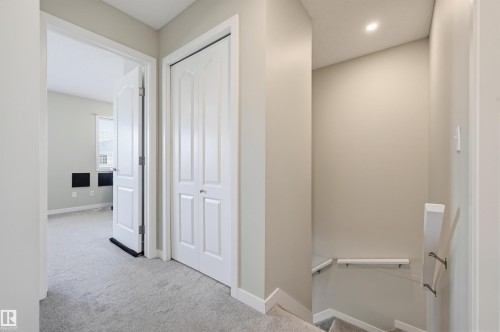 Carpeted hallway with a white bi-fold closet door and recessed lighting - 11 3380 28A Avenue Nw, Edmonton, AB - Indoor Photo Showing Other Room