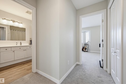 Hallway with light gray carpeting, white baseboards, and neutral wall paint - 11 3380 28A Avenue Nw, Edmonton, AB - Indoor Photo Showing Other Room