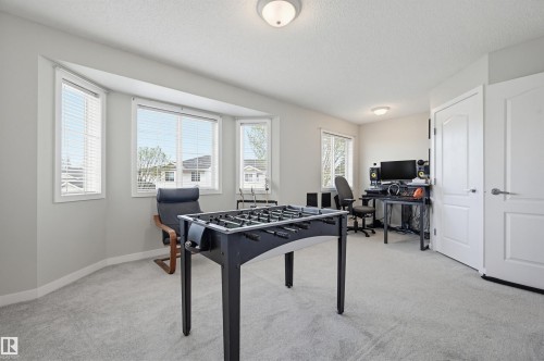 Bright room featuring a multi-pane bay window with horizontal blinds, neutral wall paint, and light-toned carpeting - 11 3380 28A Avenue Nw, Edmonton, AB - Indoor Photo Showing Other Room