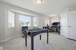 Bright room featuring a multi-pane bay window with horizontal blinds, neutral wall paint, and light-toned carpeting - 