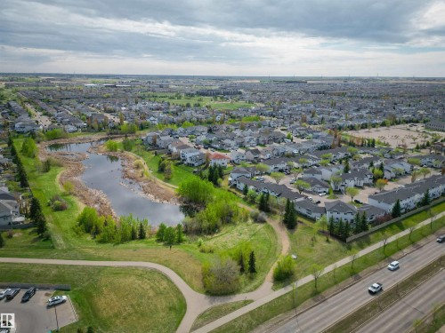 Aerial depiction of a residential area featuring a central pond with natural landscaping - 11 3380 28A Avenue Nw, Edmonton, AB - Outdoor With View