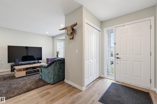 Entryway featuring a white paneled door with a sidelight, wood-finish flooring, and a bi-fold closet - 11 3380 28A Avenue Nw, Edmonton, AB - Indoor