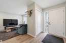 Entryway featuring a white paneled door with a sidelight, wood-finish flooring, and a bi-fold closet - 11 3380 28A Avenue Nw, Edmonton, AB  - Indoor 