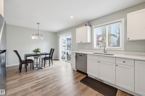 Kitchen featuring white shaker-style cabinetry, light-toned countertops, and stainless steel appliances - 11 3380 28A Avenue Nw, Edmonton, AB - Indoor Photo Showing Kitchen With Stainless Steel Kitchen With Double Sink