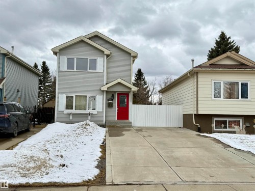 The property features a light grey exterior with white window shutters and a prominent red front door - 18425 95A Avenue, Edmonton, AB - Outdoor With Facade