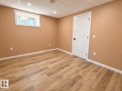 Spacious interior room featuring wood-finish flooring, neutral wall tones, and white trim - 