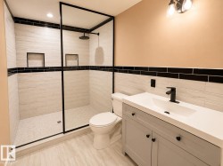 Shower enclosure featuring black-framed glass panels, a rain showerhead, and two recessed shelves - 