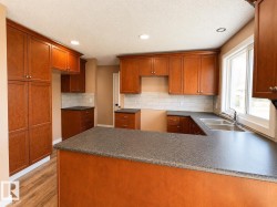 Kitchen featuring warm wood cabinetry, dark speckled countertops, and a subway tile backsplash - 