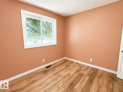 Room with neutral-toned walls, wood-finish flooring, white baseboards, and a white-framed window - 