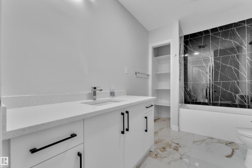 Contemporary bathroom featuring a white vanity with a quartz countertop, under-mount sink, and chrome faucet - 5118 17A Avenue Nw, Edmonton, AB - Indoor Photo Showing Bathroom
