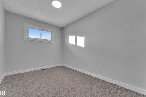 Neutral-toned room featuring a single window with white trim, recessed ceiling lighting, textured ceiling, and gray carpet flooring - 5118 17A Avenue Nw, Edmonton, AB - Indoor Photo Showing Other Room