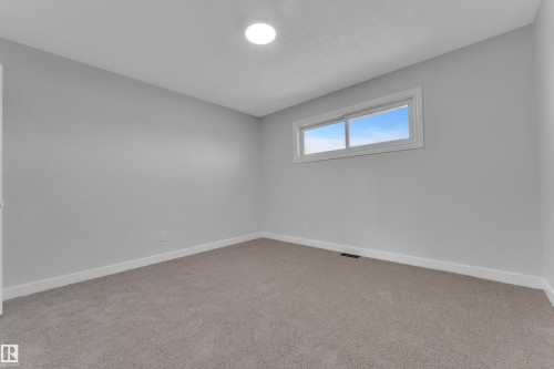 Room featuring light gray walls, plush gray carpeting, white baseboards, a horizontal window with white trim, and a ceiling-mounted flush light fixture - 5118 17A Avenue Nw, Edmonton, AB - Indoor Photo Showing Other Room