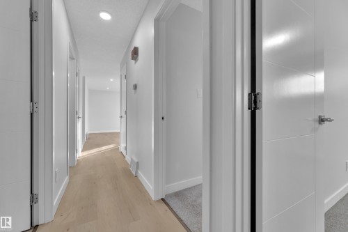 Hallway featuring wood-finish flooring, recessed lighting, white walls, and contemporary panel doors with brushed nickel hardware - 5118 17A Avenue Nw, Edmonton, AB - Indoor Photo Showing Other Room