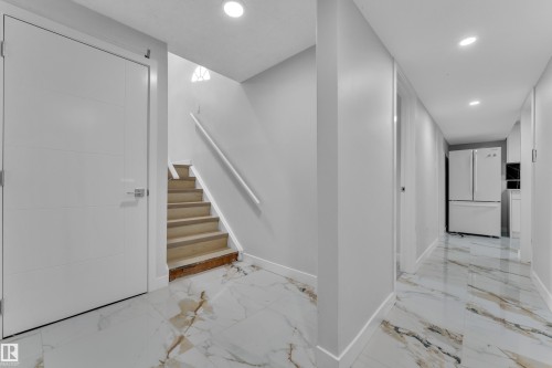 Entryway featuring white panel doors, wood-finish stairs with a white handrail, and recessed lighting - 5118 17A Avenue Nw, Edmonton, AB - Indoor Photo Showing Other Room