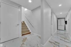 Entryway featuring white panel doors, wood-finish stairs with a white handrail, and recessed lighting - 