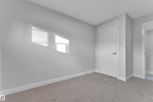 Carpeted room featuring a white interior door with chrome hardware, painted baseboards, and neutral wall tones - 5118 17A Avenue Nw, Edmonton, AB - Indoor Photo Showing Other Room