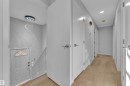 Entryway featuring a modern spiral chandelier, light wood-finish flooring, white paneled doors, and a staircase with white railings - 5118 17A Avenue Nw, Edmonton, AB  - Indoor Photo Showing Other Room 
