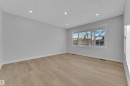 Spacious room featuring wood-finish flooring, recessed ceiling lighting, a large triple window, and white baseboards - 5118 17A Avenue Nw, Edmonton, AB  - Indoor Photo Showing Other Room 