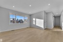Spacious room featuring light wood-finish flooring, recessed ceiling lighting, a large window with white trim, and light gray painted walls - 5118 17A Avenue Nw, Edmonton, AB  - Indoor Photo Showing Other Room 